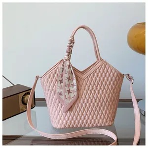 Vue détaillée d'un sac à main matelassé rose avec un élégant foulard noué à la poignée.
