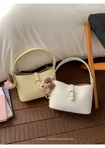 Dettaglio di borse sottobraccio eleganti crema e gialle con adorabili orsetti peluche.
