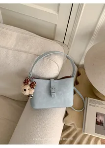 Borsa a tracolla retrò azzurra con ciondolo a forma di orso su un divano chic