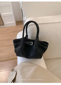 Primo piano di borsa tote minimalista in pelle scamosciata nera con fibbia su divano
