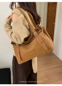 Elegantes Model trägt eine minimalistische braune Ledertasche im Retro-Stil über der Schulter.