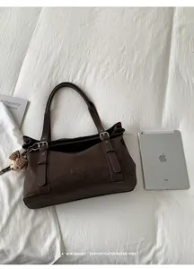 Braune Retro-Tote-Bag aus Kunstleder mit iPad als Größenreferenz auf weißem Laken.