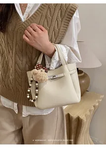 Chic cream pebble leather handbag with cute bear charm shown in a minimalist lifestyle setting