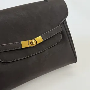 Gros plan d'un sac à main en cuir marron foncé avec fermoir tournant en métal doré
