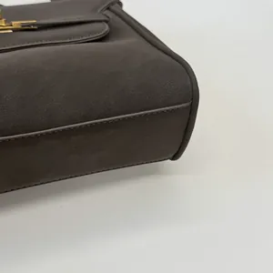 Détail en gros plan d'un sac à main en cuir marron foncé avec des coutures fines.