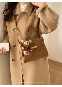 Sac à main marron vintage avec breloque ours porté avec un manteau en laine beige