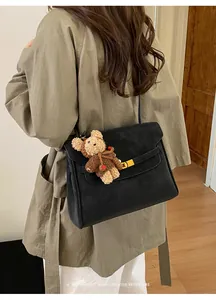 Vue détaillée d'un sac à bandoulière rétro noir minimaliste avec un joli porte-clés ours