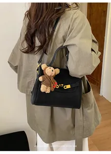 Sac à bandoulière noir vintage avec fermoir doré et un adorable charm ourson.