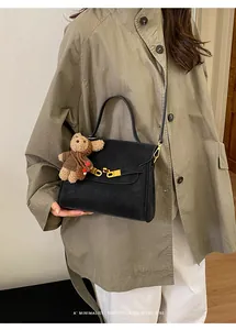 Sac à bandoulière noir de style vintage avec un charm ours en peluche porté par un modèle