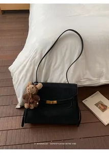 Gros plan d'un sac à main noir en daim minimaliste avec un charmant petit ours.