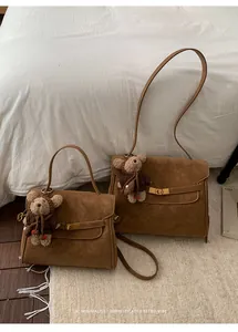 Deux sacs à main rétro en daim marron de tailles différentes avec des breloques ours.