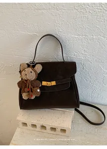 Sac à main classique en daim marron avec poignée et breloque ours sur socle en pierre