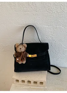 Gros plan d'un sac à main noir minimaliste pour femme avec un charmant ours brun