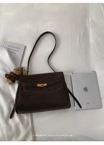 Détail d'un sac à bandoulière minimaliste en cuir marron avec boucle dorée rotative