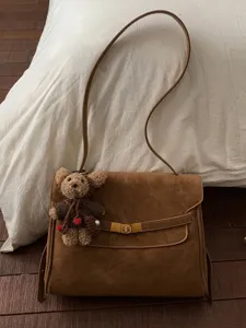 Sac à bandoulière sophistiqué en daim marron avec un joli porte-clés ours en peluche.