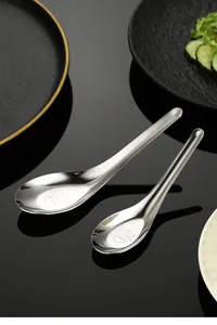 Detail view of mirror polished stainless steel soup spoons on dark background