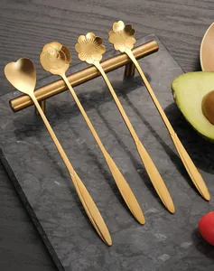Detailed macro view of four long-handled golden flower-shaped stainless steel spoons