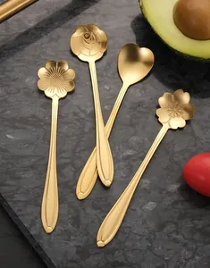 Detailed view of golden stainless steel flower-shaped stirring spoons on marble