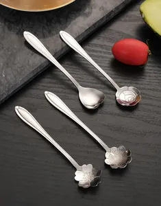 Close-up of four stainless steel spoons with floral and heart shaped heads on table