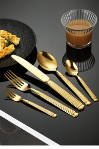 Close-up of golden stainless steel cutlery set with Roman column ribbed handles for dining