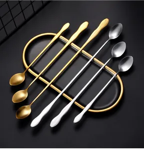 Detail of gold and silver long-handle stainless steel coffee stirring spoons on a tray