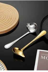 Stainless steel duckbill sauce spoons in gold and silver finishes on a reflective background
