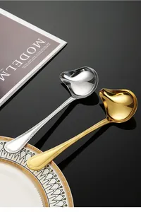 Detail view of gold and silver stainless steel sauce ladles with pouring spouts
