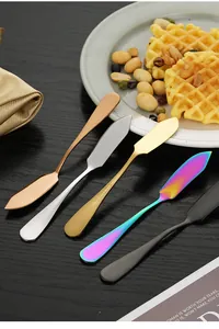 Set of stainless steel butter knives in multiple finishes on a table next to waffles