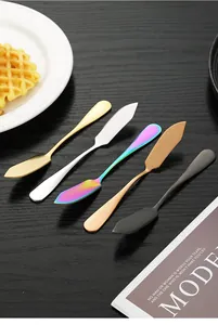 Macro view of various colored stainless steel butter knives on a dark wooden tabletop.