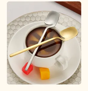 Dettaglio di cucchiai in acciaio inox spazzolato oro e argento su una tazzina da caffè.