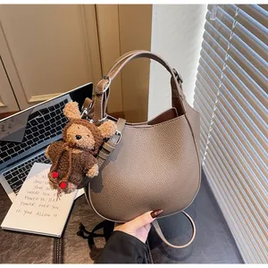 Detail of pebbled leather handbag with cute bear charm in lifestyle setting