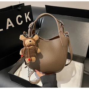 Detail of brown pebbled leather bucket bag with cute teddy bear charm accessory