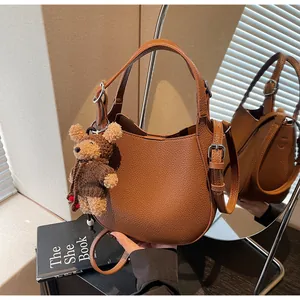 Detailed view of a brown pebble leather bucket bag featuring a cute bear bag charm.
