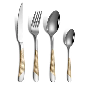 Modern stainless steel flatware set with gold textured handles on white background