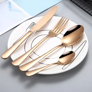 Rose gold stainless steel flatware set with knife fork and spoons on plate.