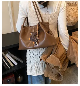 Vintage brown leather shoulder bag featuring a cute dachshund charm and tassel detail