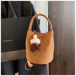 Detail einer Vintage Wildleder Eimertasche für Damen mit Plüschhandschuh-Anhänger