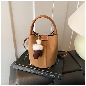 Elegante Vintage-Beuteltasche in Camel mit Pelzhandschuh-Anhänger auf einem Deko-Buch