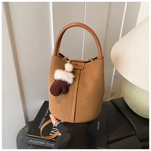 Nahaufnahme einer braunen Vintage-Eimertasche mit einem niedlichen Plüschanhänger