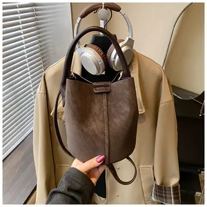 Detaillierte Ansicht einer braunen Vintage-Leder-Eimertasche vor einer schicken Jacke
