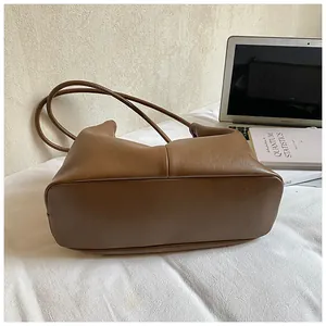 Vintage brown minimalist leather shoulder bag detail with elegant stitching and long straps.