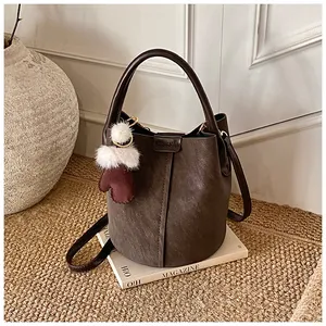 Detailansicht einer dunkelbraunen Vintage-Eimertasche aus Leder mit Plüsch-Anhänger
