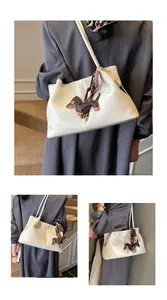 Detailed view of cream underarm shoulder bag featuring a cute dachshund charm accent