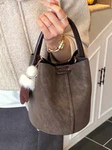 Vintage-Eimertasche aus braunem Kunstleder mit weißem Bommel-Anhänger für Damen