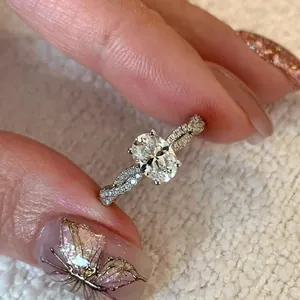 Elegante anillo plateado con circón ovalado y banda retorcida con diamantes SKU