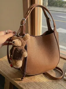 Stylish minimalist brown lychee leather bucket bag accessory with a cute teddy bear charm