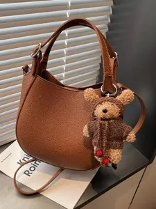 Minimalist brown pebbled leather bucket bag with top handle, crossbody strap and teddy charm