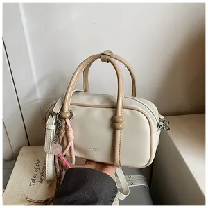 Detailed view of a stylish cream mini pillow bag featuring beige handles and strap