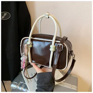 Detailed close-up view of a stylish mini brown and white pillow handbag with charms