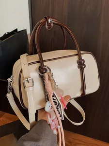 Elegant cream mini Boston bag with brown handles, shoulder strap and cute decorative charms.